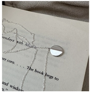 Minimalist S925 silver round pendant necklace displayed on an open book page
