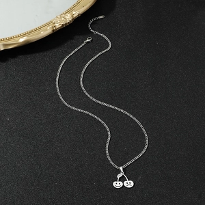 Vue détaillée du collier cerise argenté hip-hop avec pendentifs visage souriant et triste