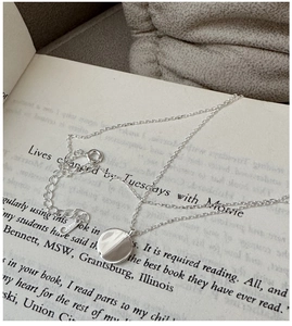 Detail of S925 sterling silver necklace with round pendant on a vintage book background