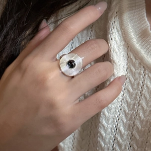 S925 sterling silver ring with concentric circular texture and black agate bead on a finger