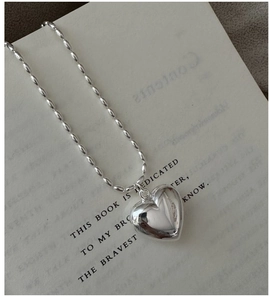 Macro detail of silver heart pendant and beaded chain on a vintage book page