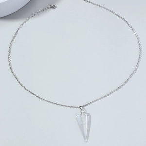 Détail d'un pendentif triangle en pierre verte sur une fine chaîne argentée