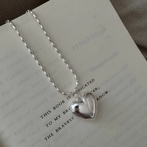 Minimalist S925 sterling silver hollow heart necklace on a bead chain displayed on a book