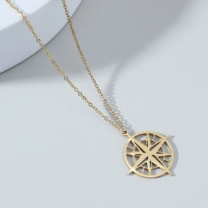 Minimalist gold North Star compass pendant necklace on a modern geometric display
