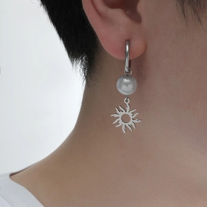 Boucles d'oreilles soleil rétro en argent avec perle blanche portées par un homme
