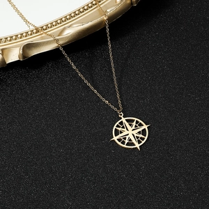 Detailed view of golden North Star compass pendant on a fine chain over black texture
