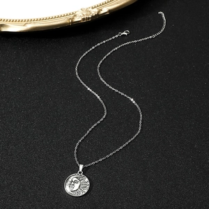 Macro detail of silver sun and moon medallion necklace on a textured black display