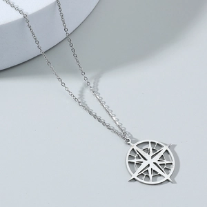 Close-up of minimalist silver star compass pendant on o-chain over a curved podium