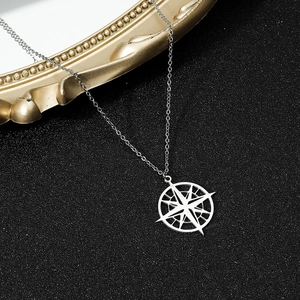 Detail shot of silver compass pendant on a fine chain with retro gold frame decor
