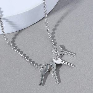 Men's silver ball chain necklace with four realistic key pendants on a minimalist display
