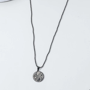 Detail of gothic yin yang skull pendant with black beaded chain on white background
