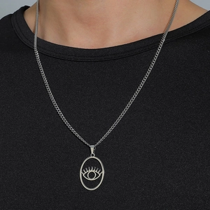 Collier pendentif Oeil d'Horus argenté porté sur t-shirt noir, style hip hop chic