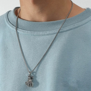 Pendentif main de squelette gothique avec chaîne argentée sur un sweat-shirt gris