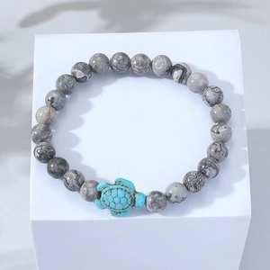 Handmade beaded bracelet with grey textured stones and a turquoise turtle charm on white