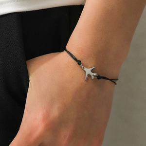 Bracelet tressé noir minimaliste avec pendentif avion argenté poli sur le poignet