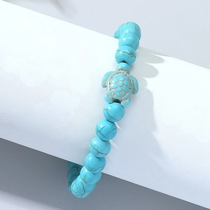 Detail of turquoise beaded bracelet with turtle charm on a white jewelry display