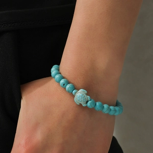 Detailed view of turquoise bead bracelet with a central sea turtle charm on wrist