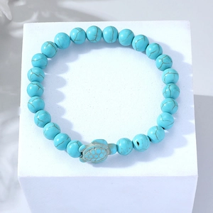 Detailed close-up of beaded bracelet featuring turquoise stones and a sea turtle charm