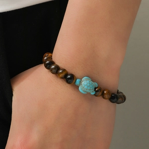 Close-up of tiger eye beaded bracelet with turquoise sea turtle charm on wrist