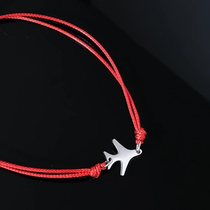 Gros plan sur un bracelet tressé rouge avec un pendentif avion en argent poli