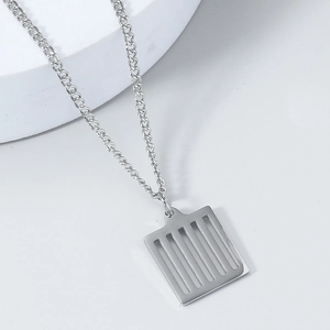Détail macro d'un pendentif rectangulaire argenté ajouré au design géométrique pur