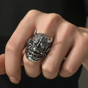 Detailed close-up of a vintage silver Hannya mask ring on a male finger in punk style