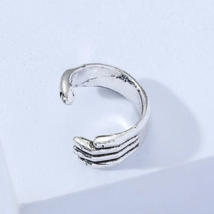 Adjustable silver skeleton hand hug ring with vintage punk texture on blue background