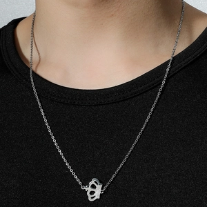 Minimalist silver crown pendant necklace in stainless steel worn by a model over black knitwear