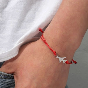 Détail du bracelet tressé rouge avec pendentif avion et nœuds coulissants ajustables