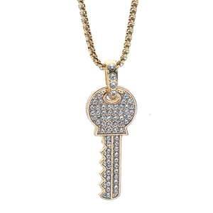 Collier avec pendentif clé dorée serti de strass brillants sur une chaîne en métal fin