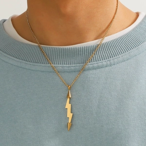 Detailansicht einer goldenen Blitz-Halskette getragen über einem blauen Strickpullover