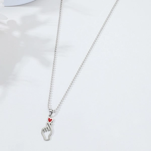 Silver bead chain necklace with cutout heart hand gesture pendant and red enamel detail