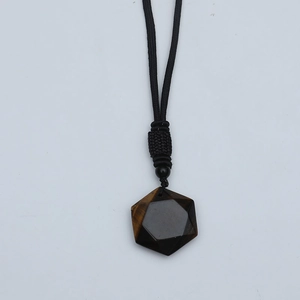 Macro shot of brown hexagram tiger eye stone pendant with black woven cord