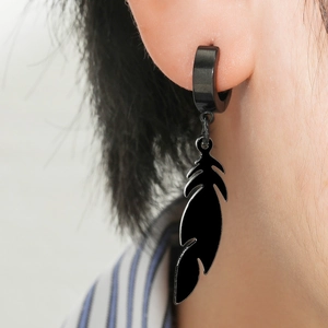 Gros plan d'une boucle d'oreille plume noire mate portée par un homme au style gothique