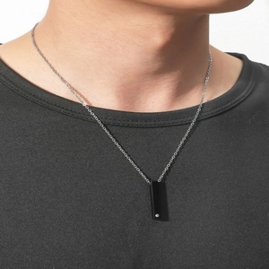 Close-up of minimalist black rectangle pendant with single small diamond on silver chain