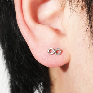Close-up of infinity symbol ear stud in polished silver metal worn on ear lobe