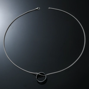 Minimalist silver chain necklace with a smooth ring pendant on a black reflective surface