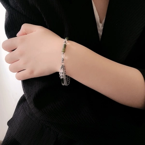 Detail of green bamboo beads and silver chain link bracelet on model's wrist