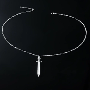 Detail of silver-tone cross sword pendant necklace on black background with curb chain