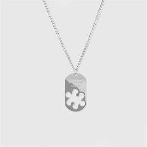 Détail macro d'un pendentif puzzle avec texte gravé sur une chaîne en acier argenté
