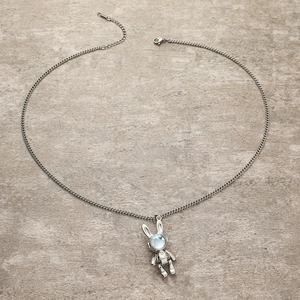 Collier lapin mécanique avec pendentif en pierre de lune bleue sur surface en pierre