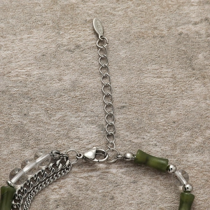 Detail of stainless steel lobster clasp and green bamboo beads on a beaded bracelet