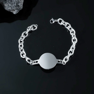 Macro view of silver stainless steel curb chain bracelet with polished round tag and clasp