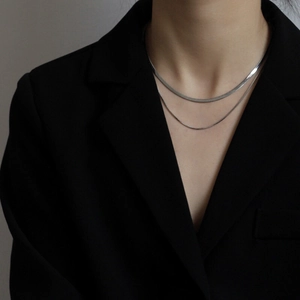 Collana a doppio strato in argento stile minimalista indossata su una giacca nera