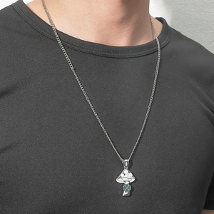 Detailed close-up of a silver mushroom pendant with white dots and a green clover on a chain