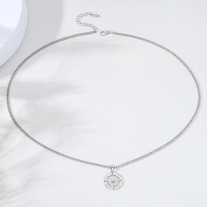 Detail of silver compass pendant necklace with adjustable chain on a minimalist background