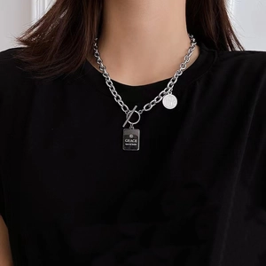 Detail of silver titanium steel chain with engraved circular and rectangular pendants
