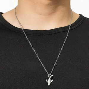 Gros plan du pendentif baleine argenté sur une chaîne fine avec une tenue noire
