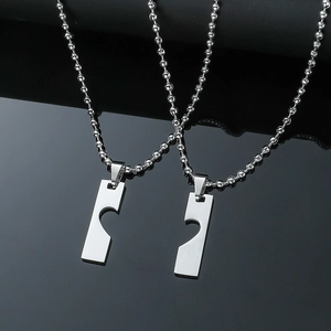Close-up of polished stainless steel couple necklaces with complementary heart pendants