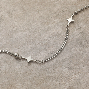 Collana geometrica in acciaio al titanio con ciondoli a stella su fondo pietra